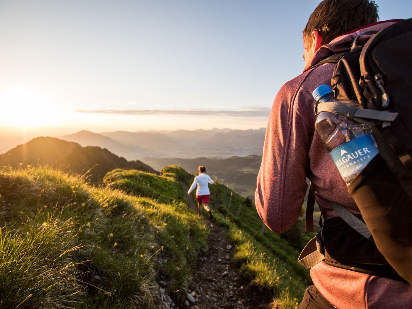 Ausgewählte Lieferanten und Erzeuger Wanderer mit Rucksack auf einem Bergpfad bei Sonnenuntergang