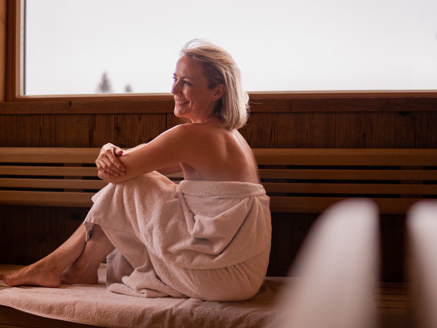 Hotel Sommer | Zubuchbare Extras für Magic Moments Frau entspannt in einem Sauna-Raum mit Holzwänden und Handtuch
