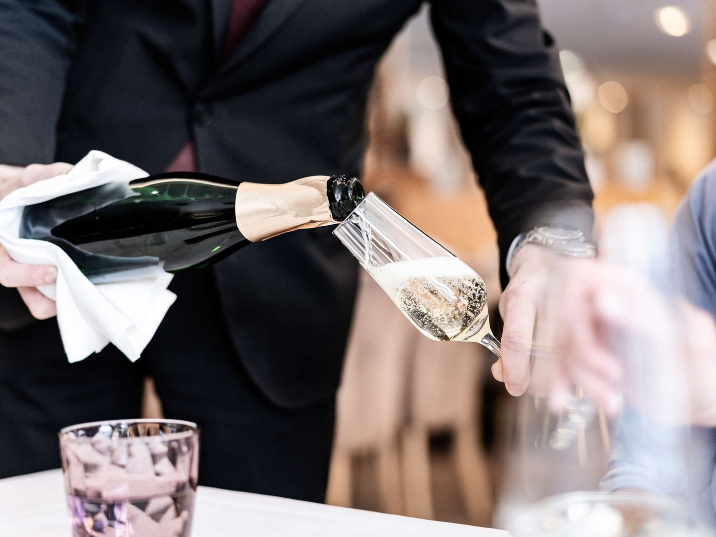 Hotel Sommer | Zubuchbare Extras für Magic Moments Kellner gießt Sekt in ein Glas in einem Restaurant