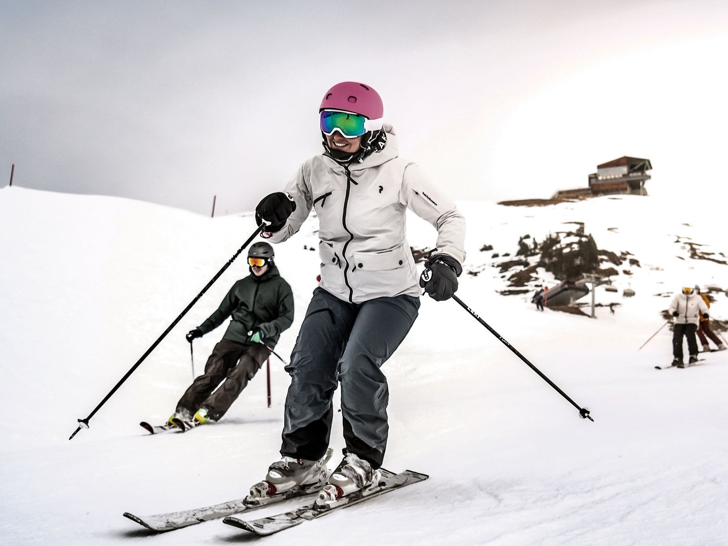Skifahren im Allgäu | Hotel Sommer Füssen Personen beim Skifahren auf schneebedecktem Hang mit Berghütte im Hintergrund